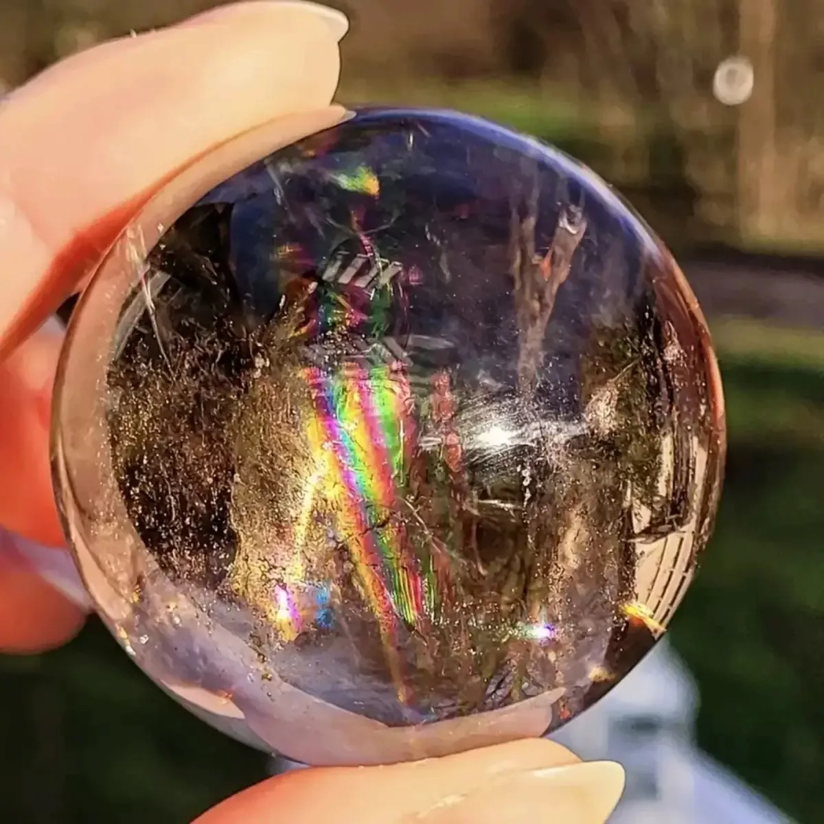 Polished smoky quartz sphere with visible internal rainbows and high clarity